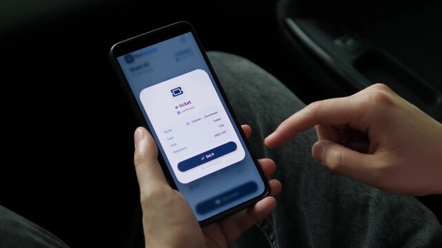 Passenger checks a bus timetable and purchases an electronic ticket on a smartphone, reflecting cashless transit, connected cities and convenient digital commuting.
