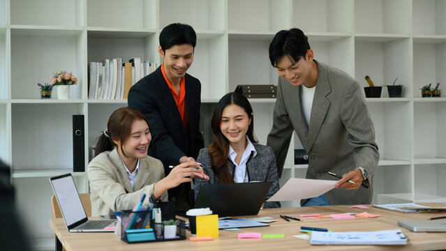 Young Asian Business Team Collaborating Around Laptop in Modern Office Workspace