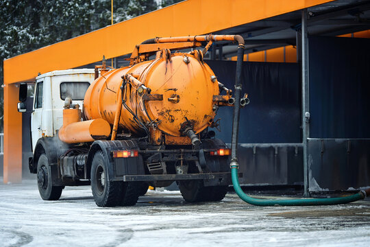 Vacuum truck connected to car wash drainage system with long hose, actively pumping out thick silt and liquid waste to keep the self service facility clean and operational. Industrial vacuum tanker