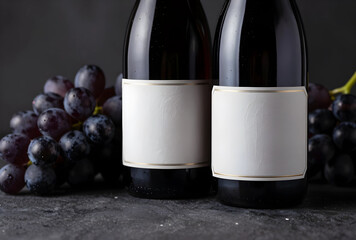 Naklejka premium Wine branding and product mockups, two dark bottles with blank labels and fresh grapes on a textured background