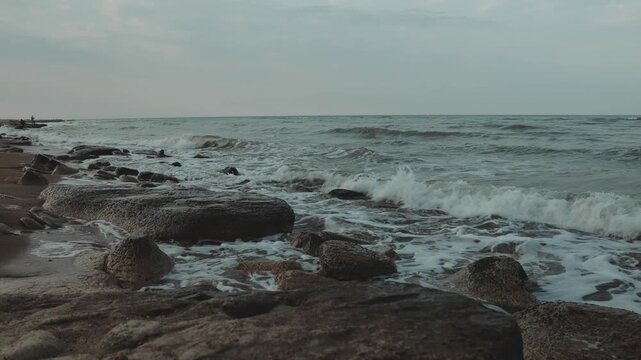on a rocky beach next to the ocean, with waves crashing in the background