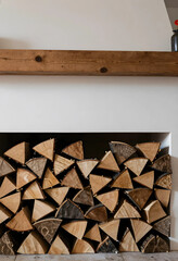 Fototapeta premium Sustainable home heating and cozy interior design, stacked firewood logs in a modern fireplace with a wooden mantel
