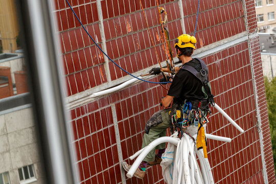 Industrial climber sealing panel joints on the facade of a high-rise building.