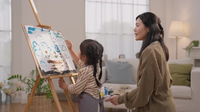 Mother and Child Painting on Easel at Home, Sharing Family Creativity Through Art, Learning Colorful Lesson Together Near Bright Window in Warm Living Room