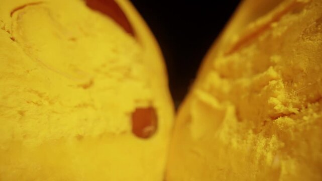 Dolly slider, close up. Sliced Canistel Fruit Reveals Dense Yellow Flesh and Seeds on a Glossy Black Surface, Showcasing Tropical Freshness and Healthy Eating