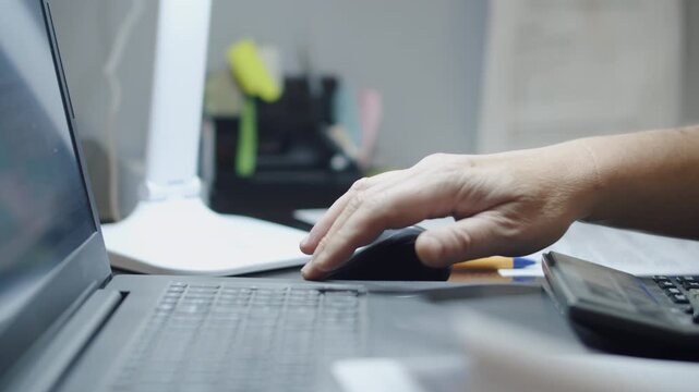 Hand Using Computer Mouse Beside Laptop at Office Desk