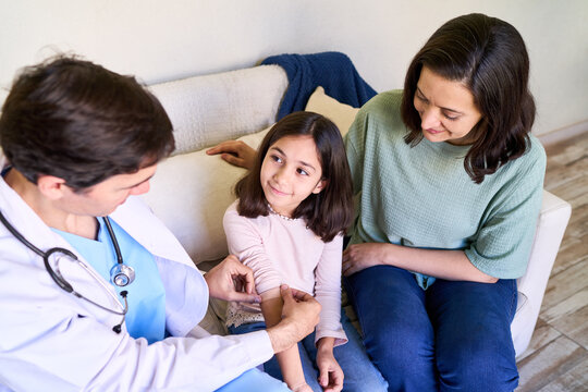 Pediatric home healthcare and doctor house call, pediatrician examining a young girl with her mother in a bright living room