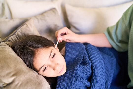 Parental care for sick child, mother cleaning daughter's ear with cotton swab at home, family healthcare and wellness