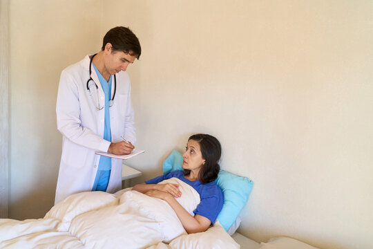 Home healthcare and doctor house call, male physician consulting with a female patient resting in bed at home