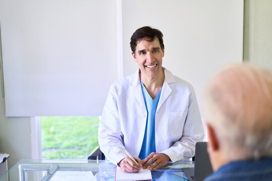 Home healthcare and doctor house call, smiling male doctor consulting with an elderly patient in a bright living room