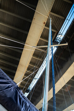 Sailing yacht metal mast and rigging with modern bridge concrete construction background.
