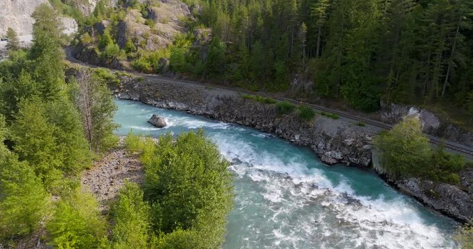 Top down view of fast moving river surrounded by pine forest. Canada 