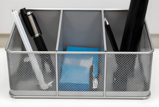 Office organization and productivity, mesh desk organizer with pens and office supplies on a clean white background