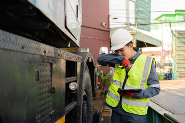 Fototapeta premium Man conducting lifting equipment inspection holds a tablet and stylus while coughing into his elbow beside a truck crane