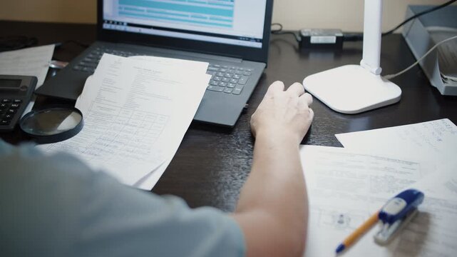 Person Working With Documents and Laptop at Office Desk