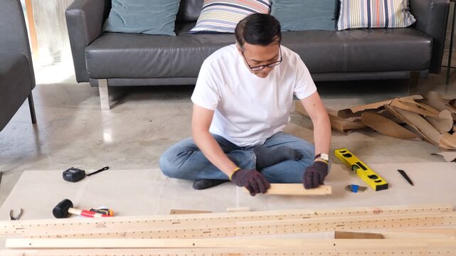 Furniture assembly old man with wood tool for home sofa project, focused flat pack builder on living room floor