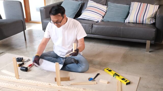 Furniture assembly man using tool on wood floor in living room building flat pack shelf table near sofa cushion