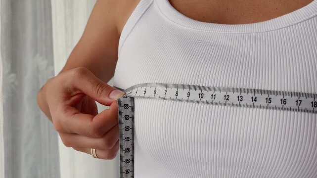 Woman measuring bust size with tape for body measurement and fitness progress.