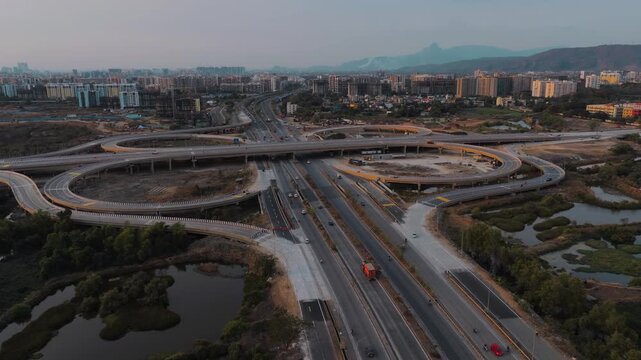 Aerial view of Navi Mumbai, Maharashtra, India, showcasing modern highway interchanges, elevated roads, green surroundings, water bodies, and rapidly developing urban areas.