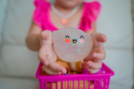 Child hands squeezing a transparent glitter dumpling shaped squishy toy