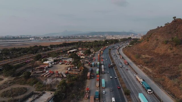 Aerial view of the Uran Panvel Road corridor near Navi Mumbai, showcasing a busy highway, modern urban development, high-rise buildings, ongoing construction, and scenic hills in the background.