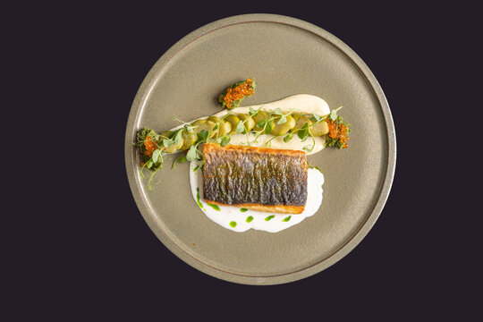 Crispy skin fish fillet served with salmon caviar, creamy pur&eacute;e, and microgreens top view on grey plate