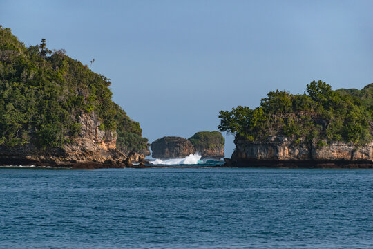 Scenic Tiga Warna Beach in Malang, East Java, Indonesia, featuring clean sandy shores, calm blue seawater, small islands and dramatic coastal cliffs surrounded by pristine tropical nature