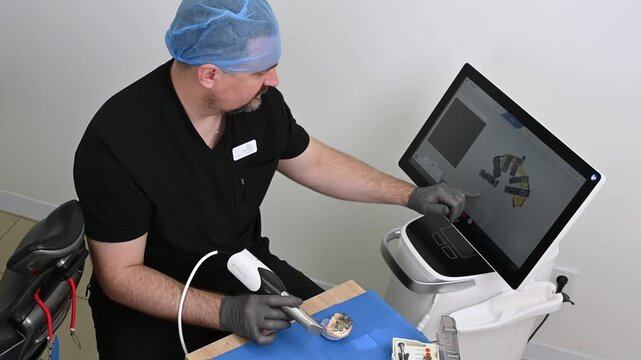 A dental technician uses a 3D optical scanner to digitize a physical dental model, transferring precise three-dimensional data to a computer for digital dental design and CAD CAM manufacturing no face