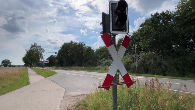 Railway crossing signal and crossbuck beside rural road and pedestrian bicycle path