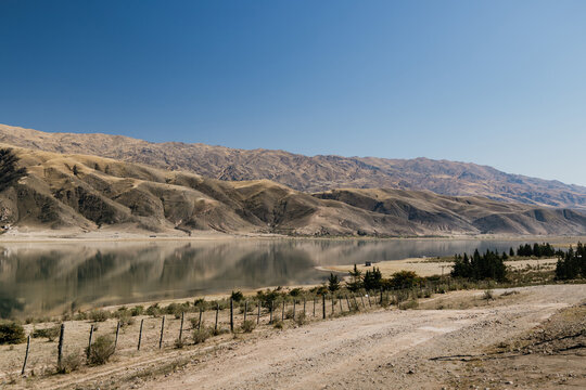 La angostura dam lake in tucuman, argentina, reflecting dry mountains and clear blue sky during winter, with provincial route 307 traversing the arid landscape