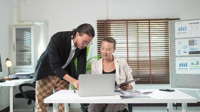Frustrated manager berating a tired employee for making a mistake while working on a business financial report and yawning in a modern office with documents and laptop