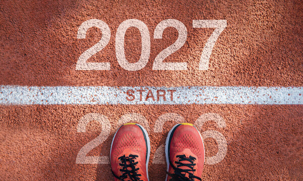 New Year 2027 concept. The beginning of success. The message "2027" is written on a running track. A male runner is preparing for the new year. The ideas concern challenges, career paths, and change.