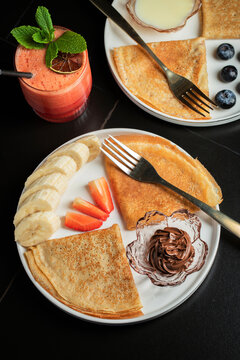 A plate of crepes filled with chocolate spread and topped with banana slices and mint