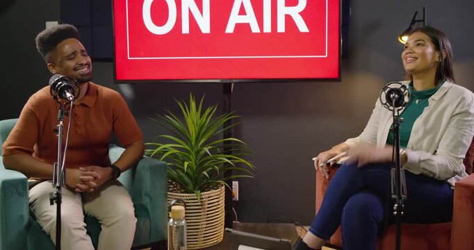 African American co-hosts recording with mics in studio laughing, noting after ON AIR sign lighting