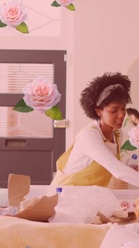 Animation of flowers over happy diverse couple recycling at home