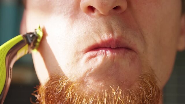 Slow Motion Close Up of a Bearded Man Shaving Facial Hair on His Cheek with an Electric Trimmer, Showing Grooming, Skin Care And Daily Hygiene Routine