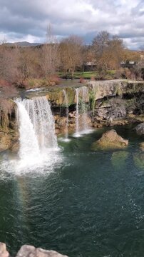 Vertical panning right shot of Pedrosa de la Tobalina waterfall and river in Burgos Spain