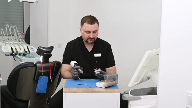 A dental technician uses a 3D optical scanner to digitize a physical dental model, transferring precise three-dimensional data to a computer for digital dental design and CAD CAM manufacturing no face