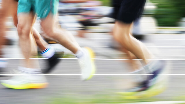Motion-blurred runners competing in a road race, creating a dynamic sense of speed, movement, energy, and athletic performance