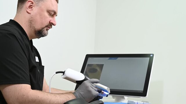 A dental technician uses a 3D optical scanner to digitize a physical dental model, transferring precise three-dimensional data to a computer for digital dental design and CAD CAM manufacturing no face