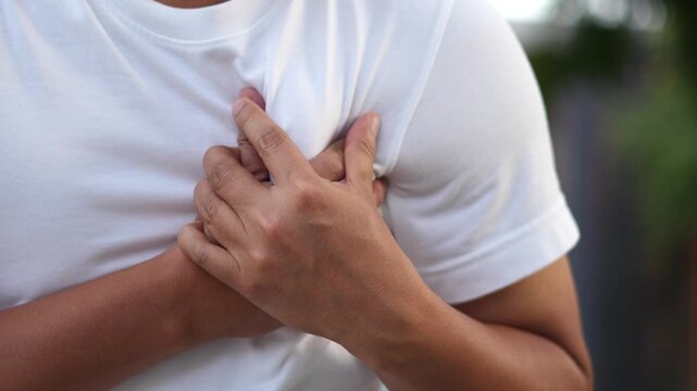 Men have chest pain. hand hold chest with heart attack symptoms, caused by heart disease, leak, dilatation, enlarged coronary heart, press on the chest with a painful expression.	