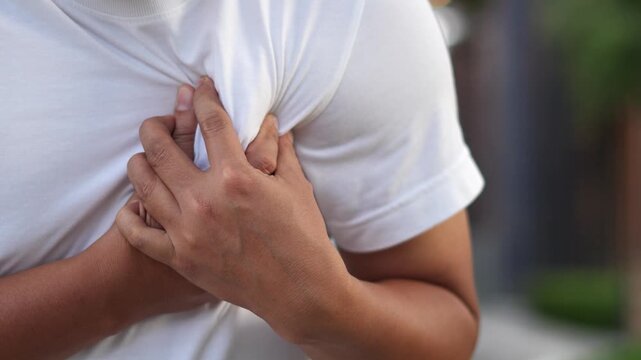Men have chest pain. hand hold chest with heart attack symptoms, caused by heart disease, leak, dilatation, enlarged coronary heart, press on the chest with a painful expression.	
