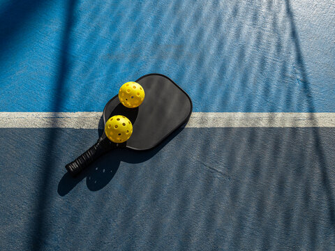 Pickleball sport with paddle and yellow balls on court