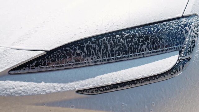 Manual wash with foam. Hands washing car during auto detailing. Car wash. Car in washing process. Carwash station. Hand washing spraying in garage. Professional car valeting
