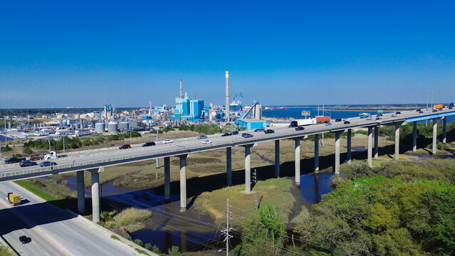 Winding salt marsh creeks meander beneath Interstate 526 overpasses near Cooper River industrial terminals. Multi lane bridges channel heavy freight transit across North Charleston, SC