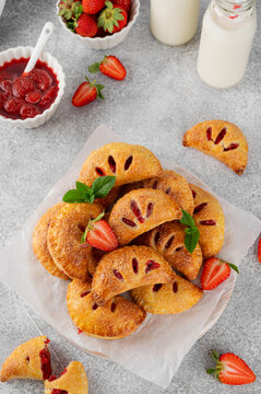 Mini close pies or hand pies with strawberries on a concrete background. Summer dessert. Top view, copy space