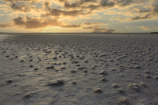 Golden hour sunset over a vast salt flat with textured ground