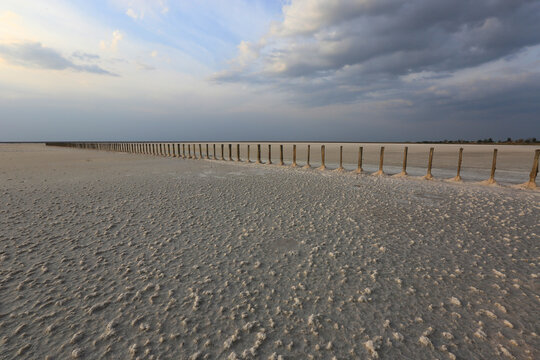 Wooden posts in a vast salt flat under a dramatic cloudy sky
