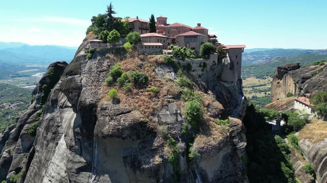 Aerial view of Holy Trinity monastery perched on massive cliff rock formation in Meteora near Kalambaka Thessaly Greece summer landscape stock video. High quality 4k footage