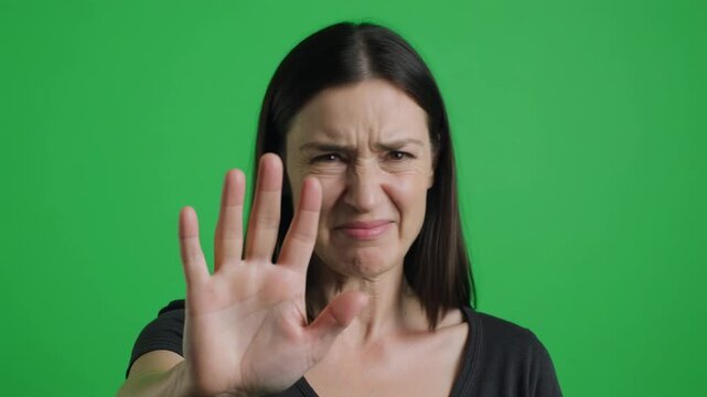 Woman's disapproval gesture against green screen with subtle facial expression shifts